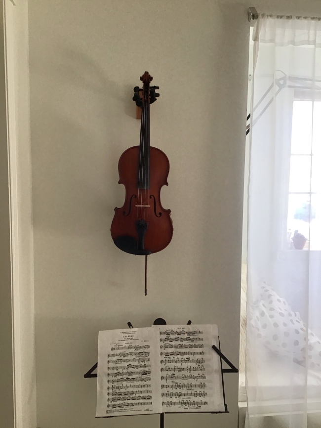 Teen girl room ideas-violin hanging on wall with music stand and sheet music.